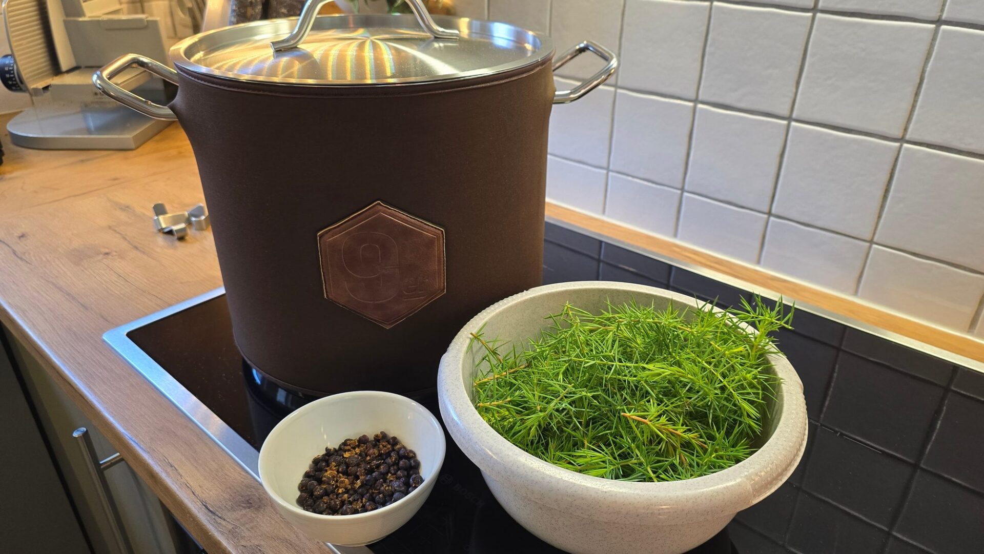 Prototyp vom 9er auf dem Herd, davor Wacholderzweige und Wacholderbeeren für ein Kräuterbier